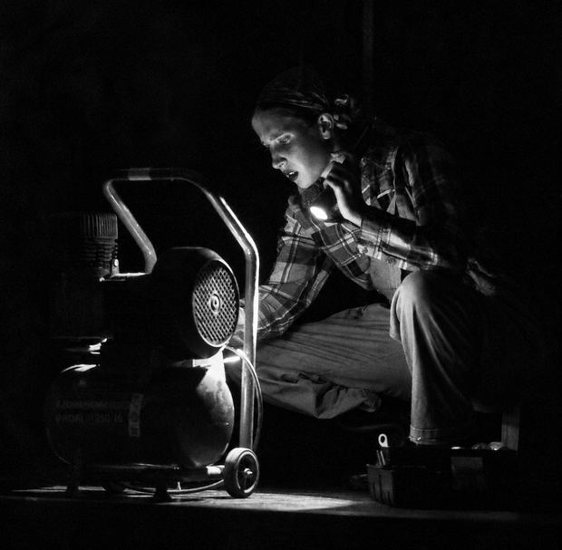 Szenenfoto: Eine Person mit Taschenlampe an einem Generator